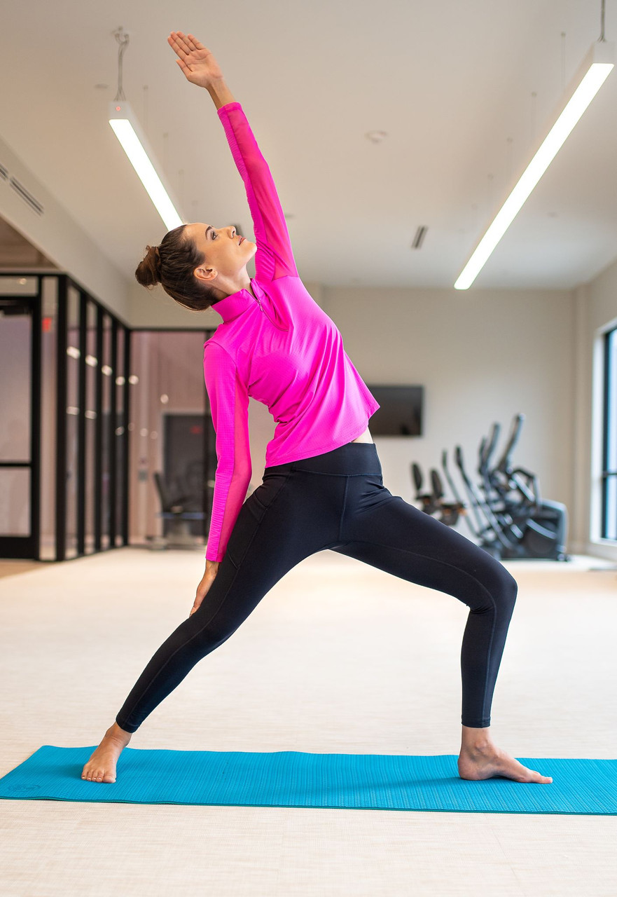 Image of a woman wearing IKBUL hot pink mock neck top and black performance leggings