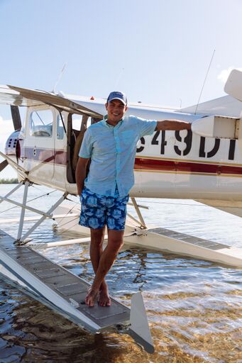 A lifestyle image from Southern Tide showing a man and a private plane landed on the water. 
