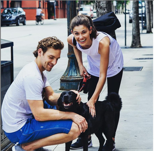 Image of couple wearing TASC apparel walking a dog.