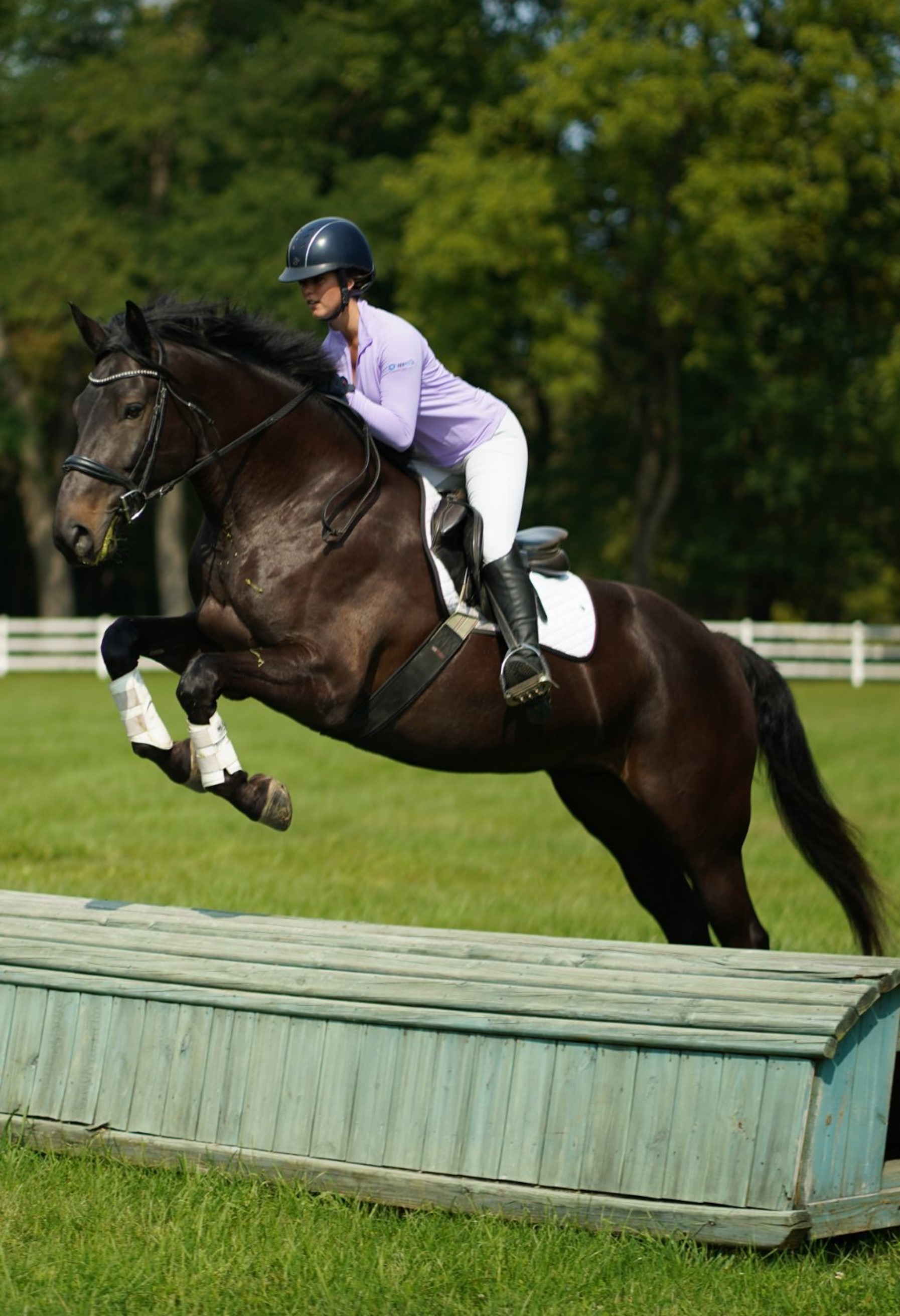 A lifestyle image from IBKUL showing a woman wearing an IBKUL top, jumping a horse 