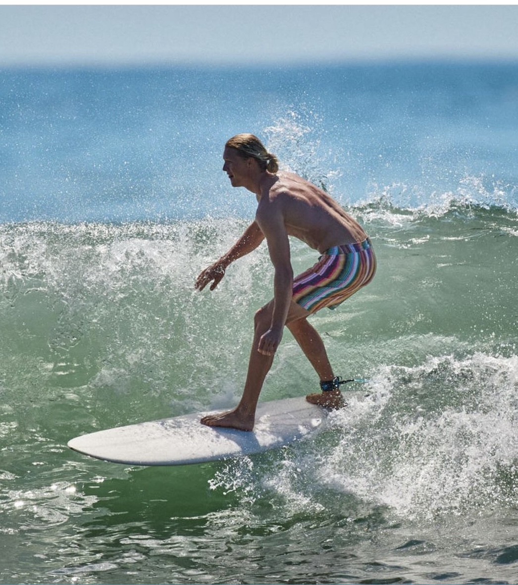 A lifestyle image from Prana showing a man surfing. 